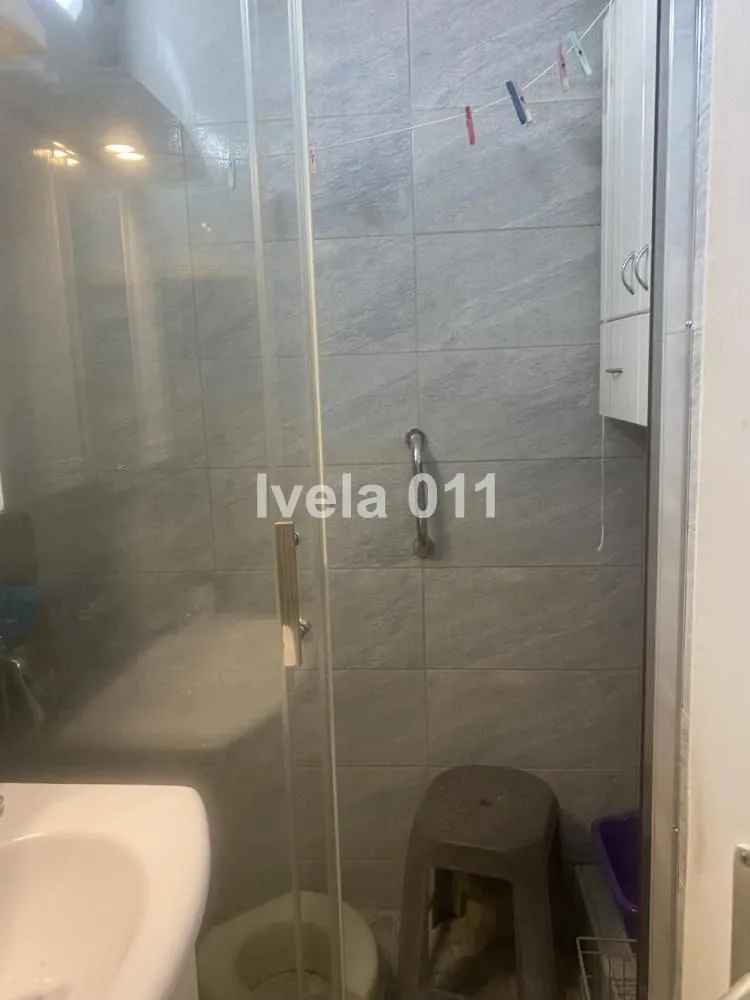 Pogled na kupatilo sa tuš kabinom obloženom sivim pločicama.