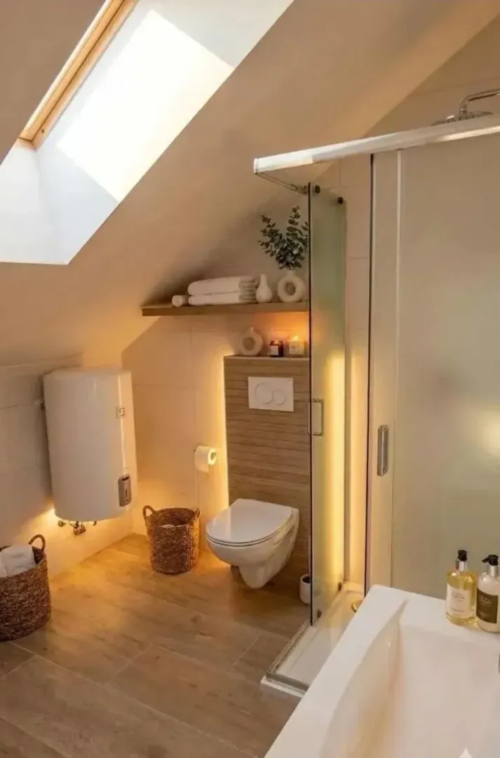 Kupatilo u potkrovlju sa tuš kabinom, WC šoljom i krovnim prozorom.