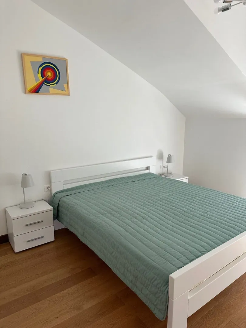 Bright bedroom with a double bed, white nightstands, and lamps.