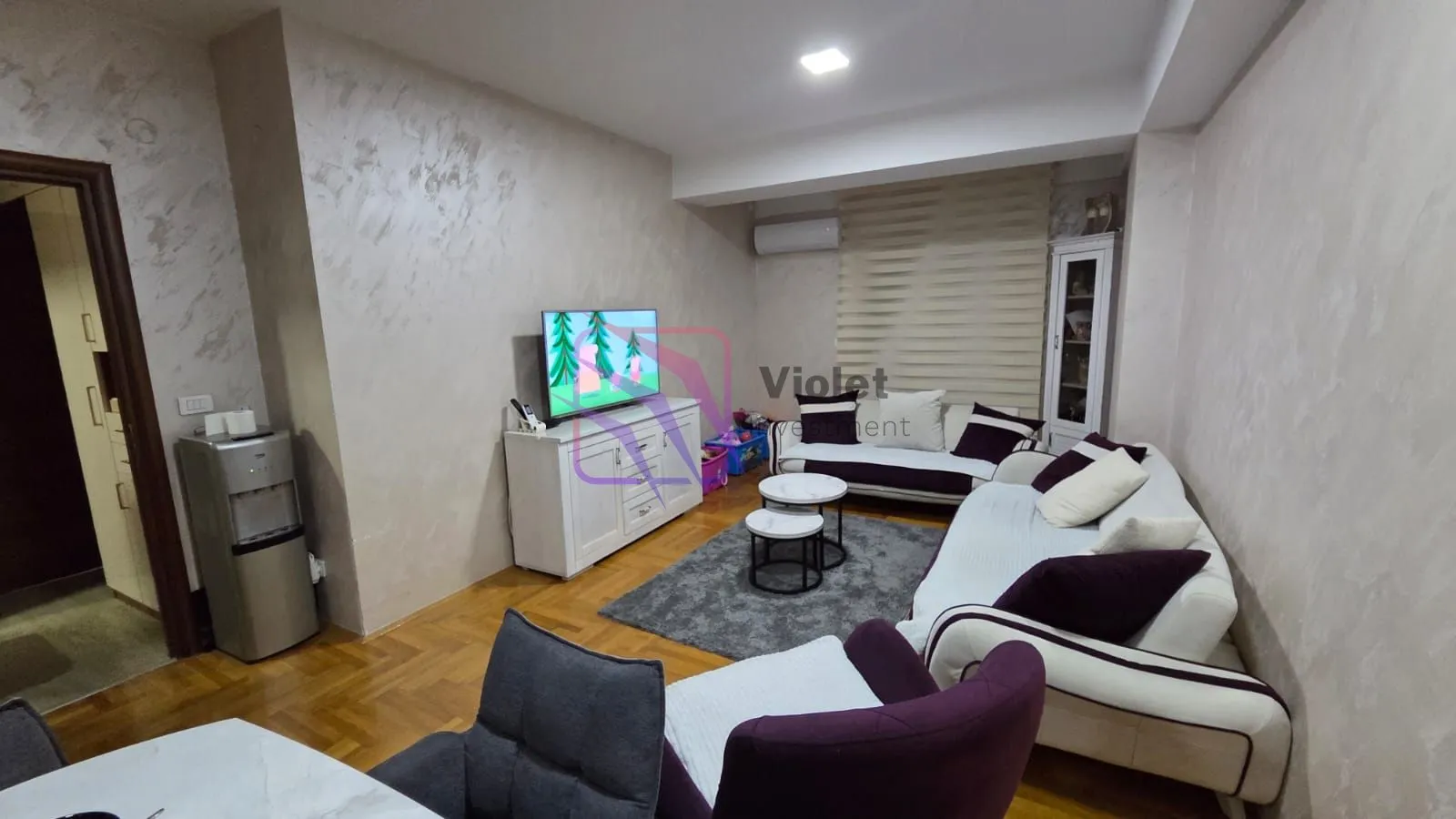 Dnevna soba sa garniturom, TV-om i trpezarijskim stolom u prvom planu.