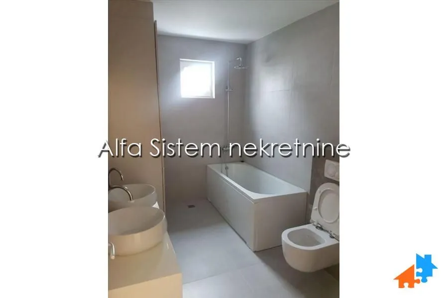 Moderno kupatilo sa kadom, dva umivaonika i toaletom.