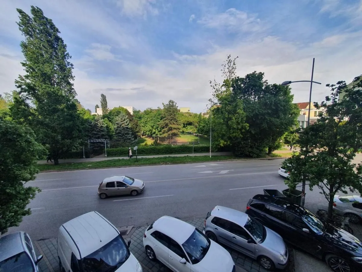 Pogled sa prozora na ulicu, park i zelene površine.