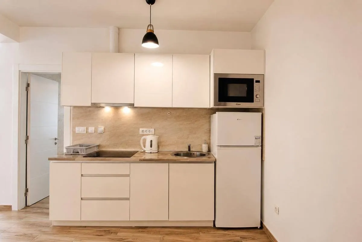 Compact white kitchen with built-in appliances and refrigerator.