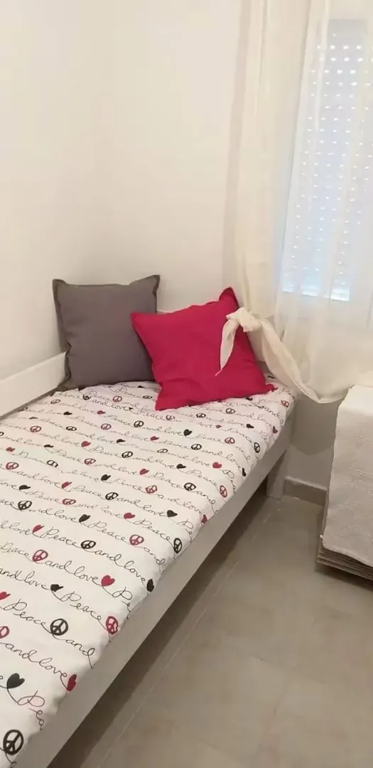 Children's bedroom with a bed and pillows by the window.