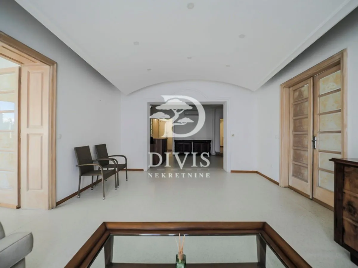 Spacious living room with wooden doors and a glass coffee table.