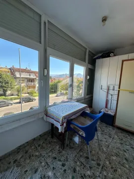 Zastakljeni balkon sa stolom, stolicom, ormarom i pogledom na okolinu. - image 5