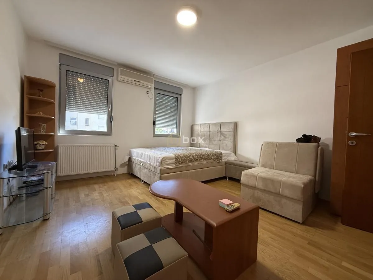 Furnished bedroom with a double bed, armchair, and TV cabinet.