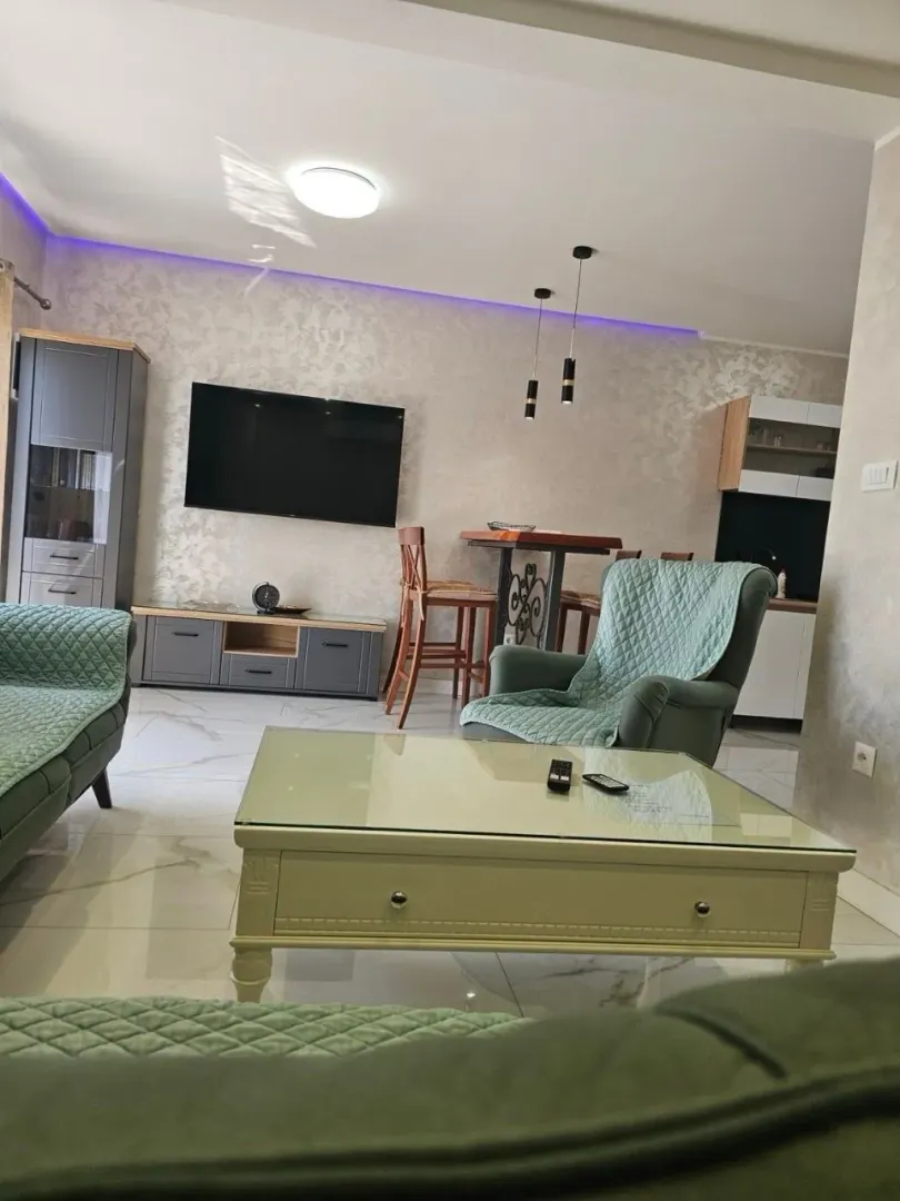 Living room with seating furniture, coffee table, and wall-mounted TV.