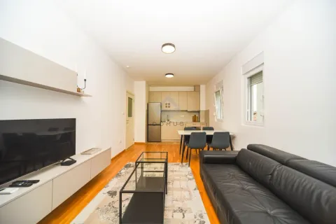 Living room with a sofa, TV, and an adjoining dining area. - image 2