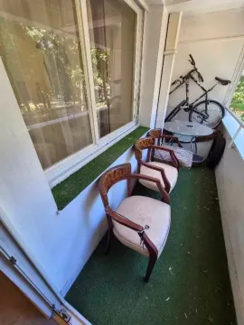 Small covered balcony with artificial turf, chairs, and a bicycle. - image 10