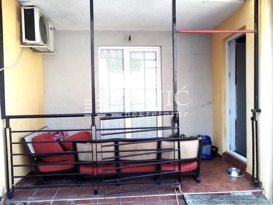 Covered terrace with seating furniture and metal railing.