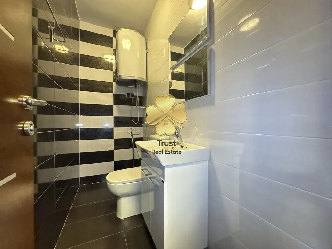 Manje kupatilo sa bijelim lavaboom, wc šoljom i bojlerom.