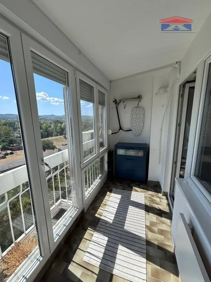 Zastakljeni balkon sa pločicama na podu i pogledom na okolinu.