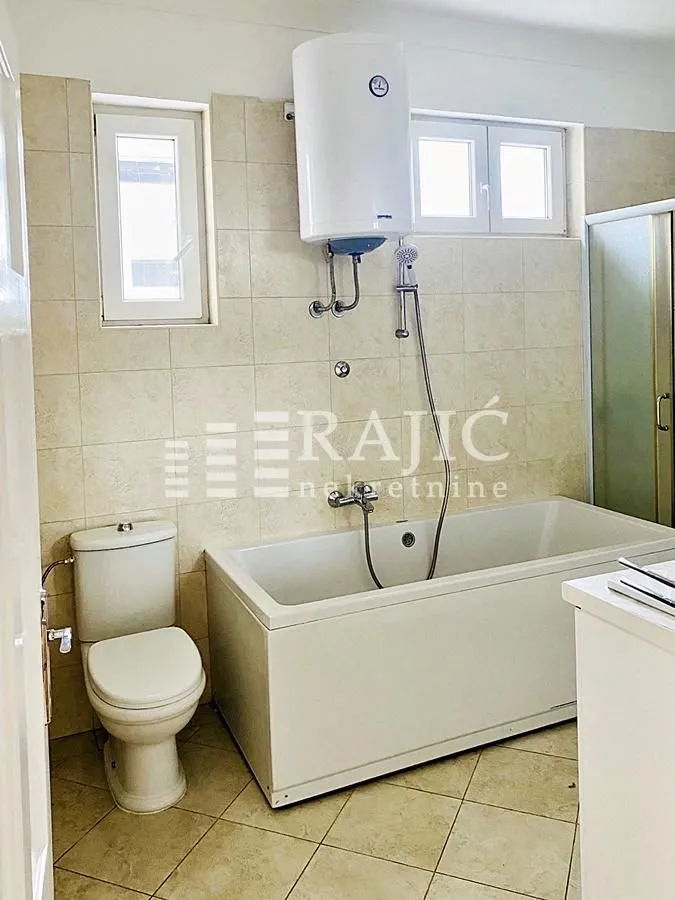 View of the bathroom with a bathtub, toilet and water heater.