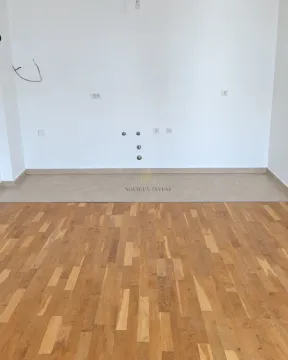 Empty kitchen space with utility connections on a white wall and wooden parquet flooring. - image 5