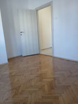 An empty room with varnished parquet flooring and an open door. - image 2