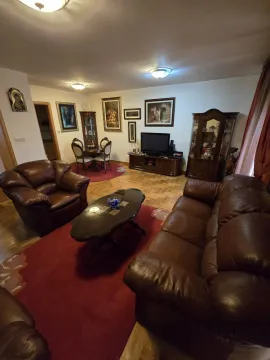Living room with brown leather sofas, wooden furniture, and a red rug. - image 4