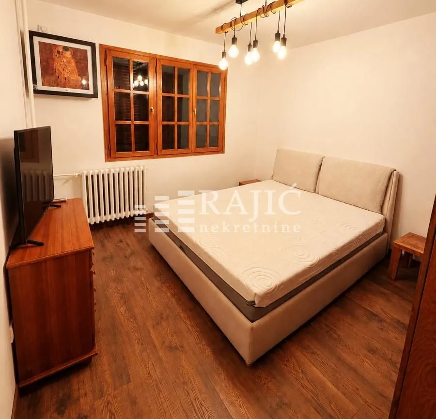 Bedroom with a double bed, wooden flooring, and a window with wooden shutters.