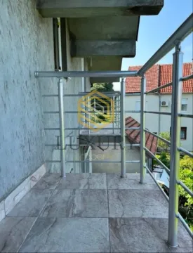 Popločani balkon sa metalnom ogradom i pogledom na okolne zgrade. - image 4