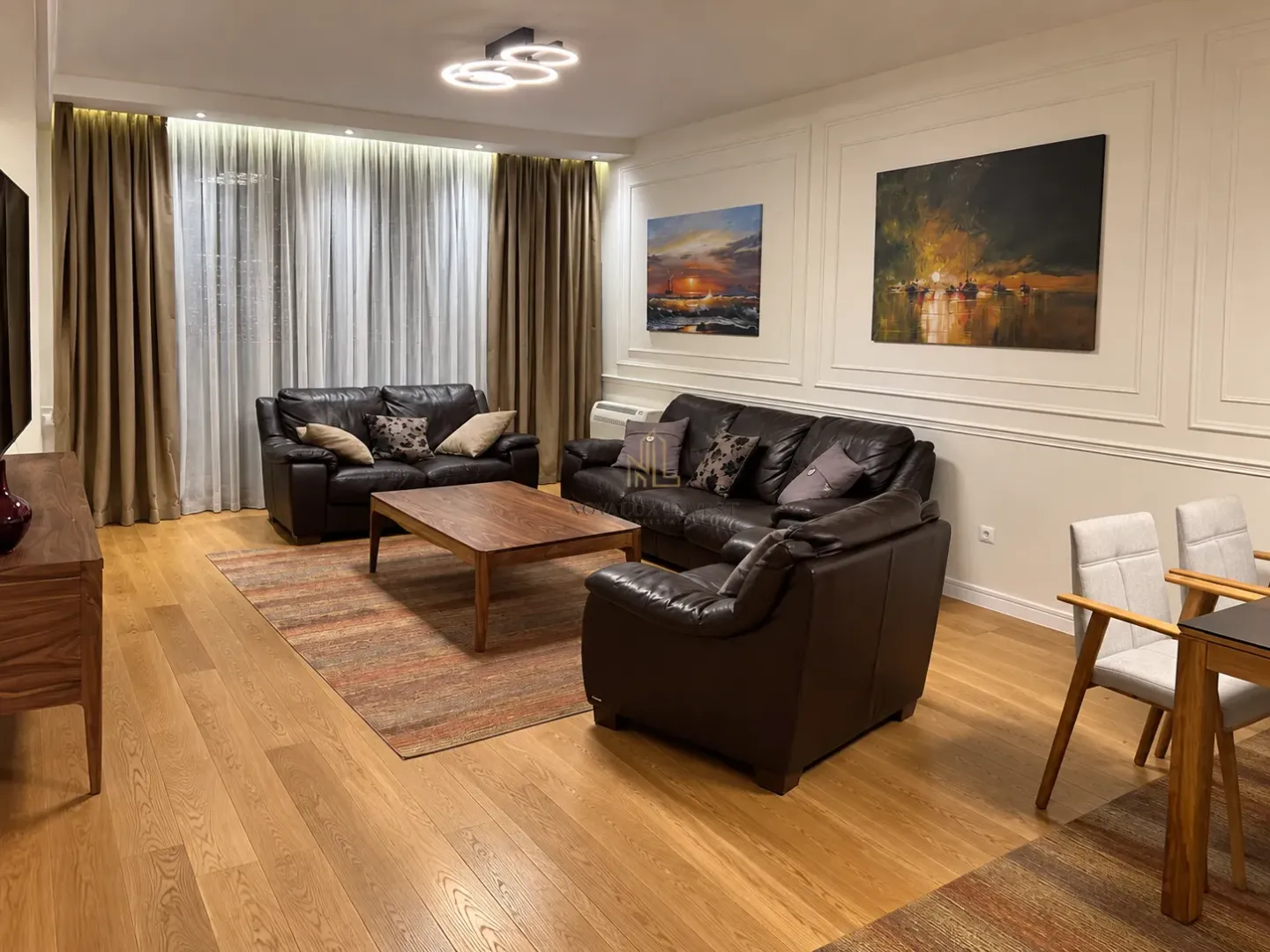 Spacious living room with leather sofas and wooden flooring.