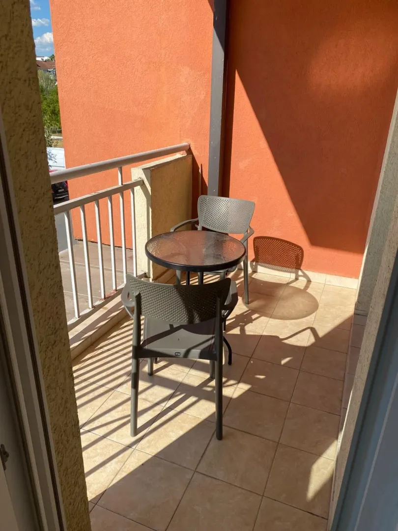 Manji natkriveni balkon sa garniturom za sedenje i stočićem.