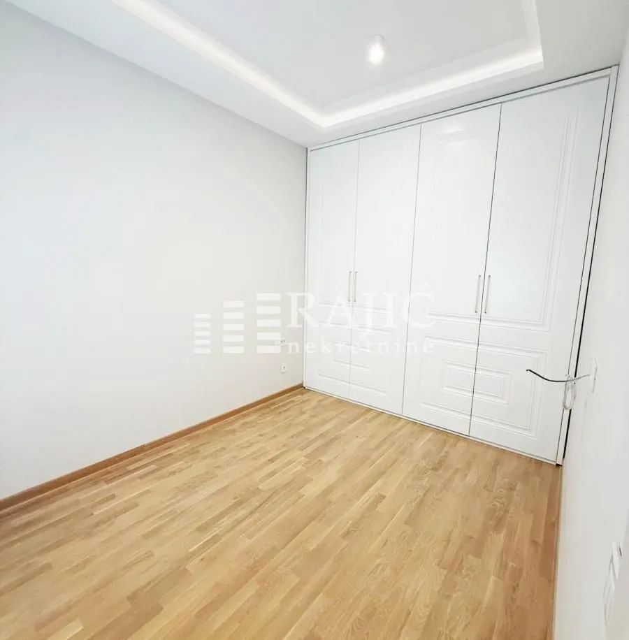 Empty bedroom with a built-in wardrobe and wooden flooring.