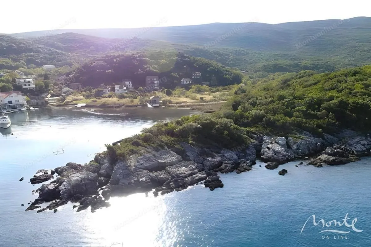 Pogled na obalu i okolni pejzaž sa brdima i šumom.