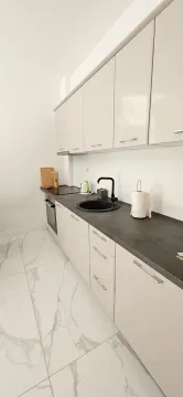Moderna kuhinja sa svijetlim elementima i tamnom radnom pločom. - image 9