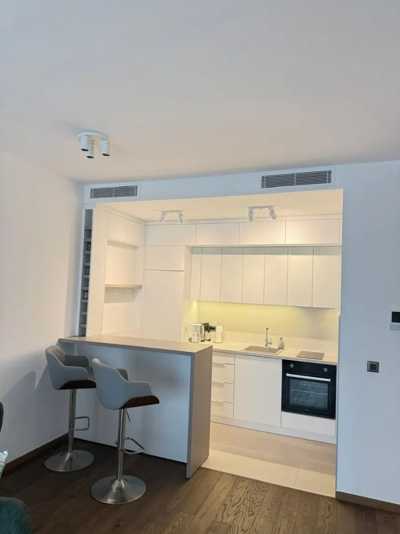 Modern white kitchen with a breakfast bar and bar stools.
