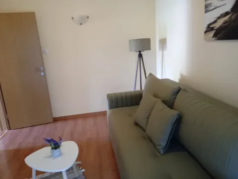 Living room with a green sofa, a small coffee table, and a floor lamp. - image 2