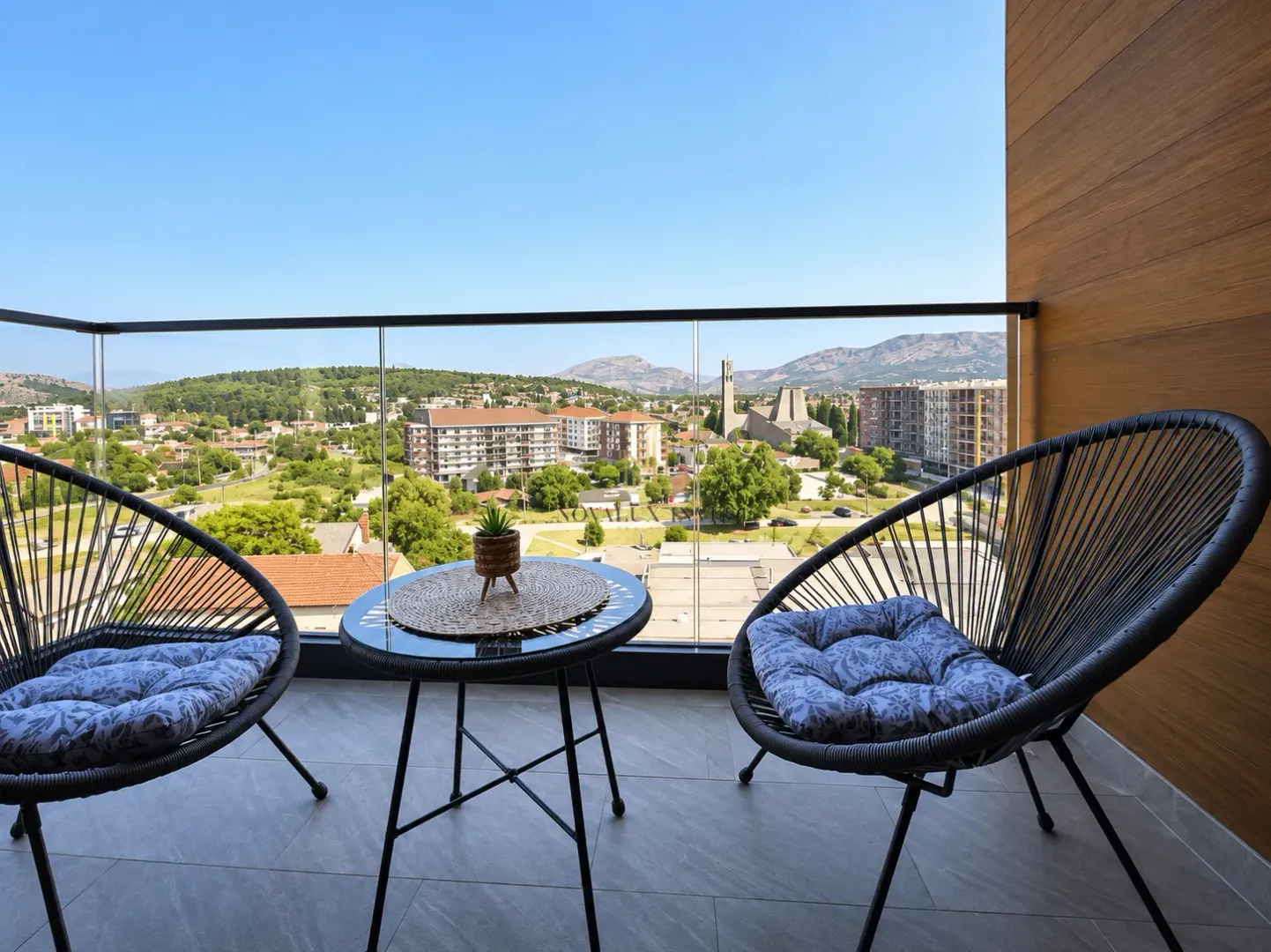 Furnished balcony with a table, chairs, and a city view.