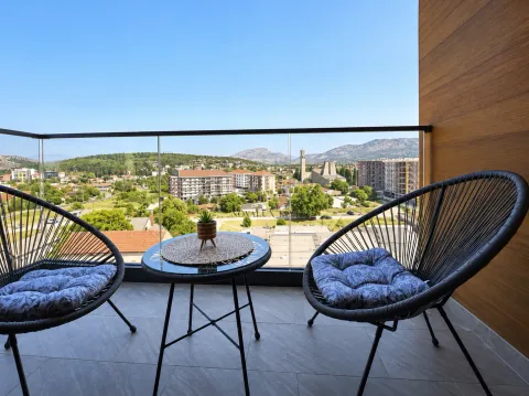 Furnished balcony with a table, chairs, and a city view. - image 13