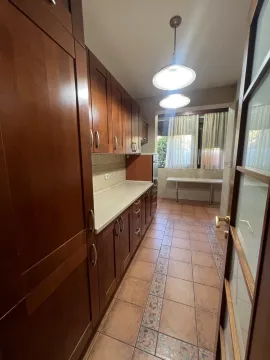 A long kitchen with wooden cabinets and tiled flooring. - image 18