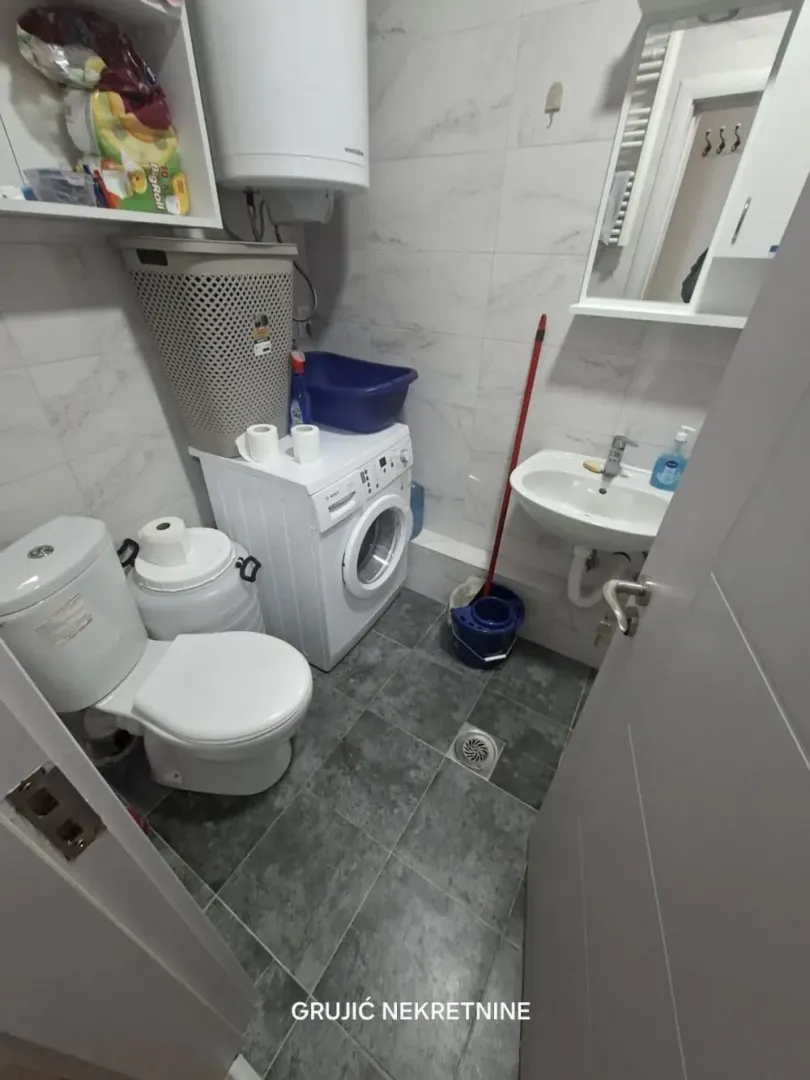 Small bathroom with a toilet, washbasin, washing machine, and water heater.