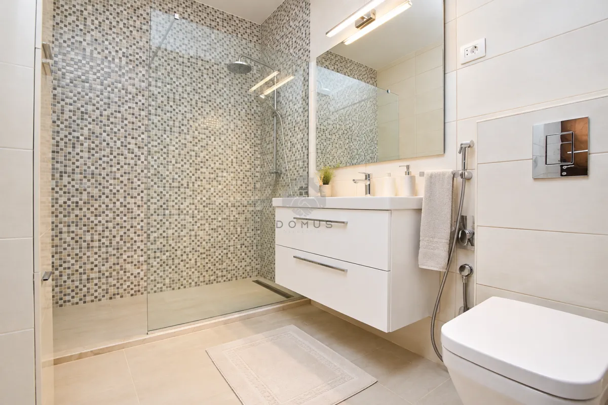 Moderne kupatilo sa tuš kabinom, umivaonikom i ugradnom wc šoljom.
