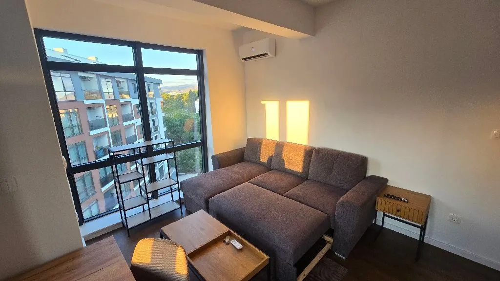 Living room with a sectional sofa, coffee table, and large window with a view.