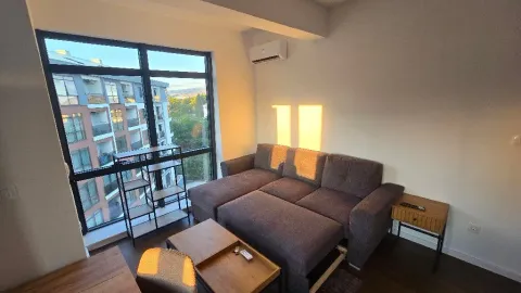 Living room with a sectional sofa, coffee table, and large window with a view. - image 11
