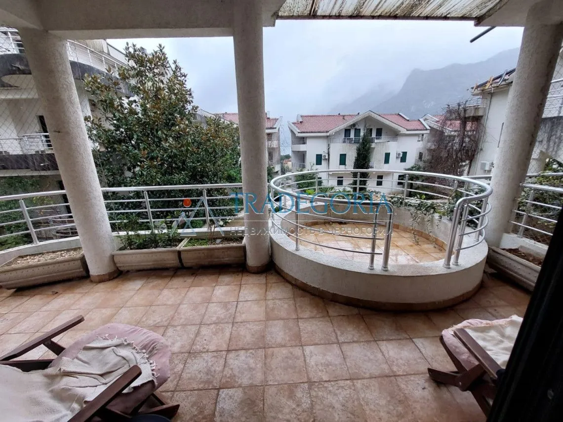 Velika natkrivena terasa sa keramičkim pločicama i pogledom na okolne zgrade i brda.