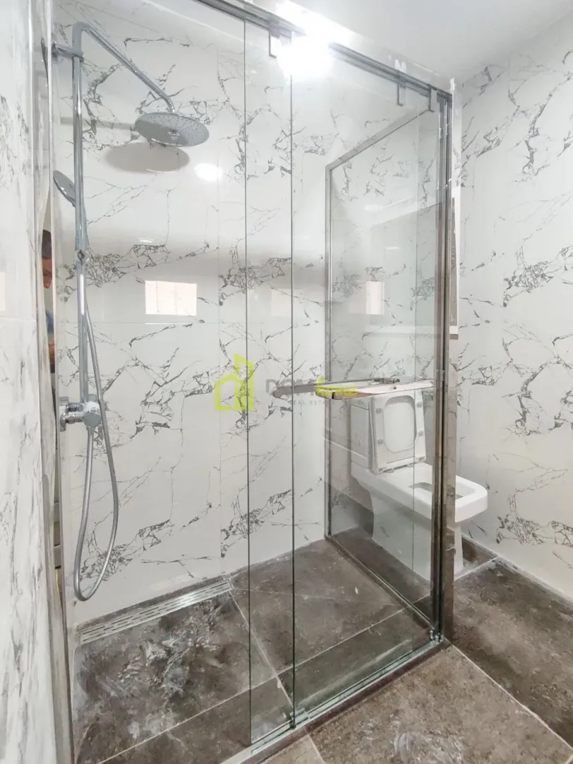 Modern bathroom with a walk-in shower lined with marble-patterned tiles.