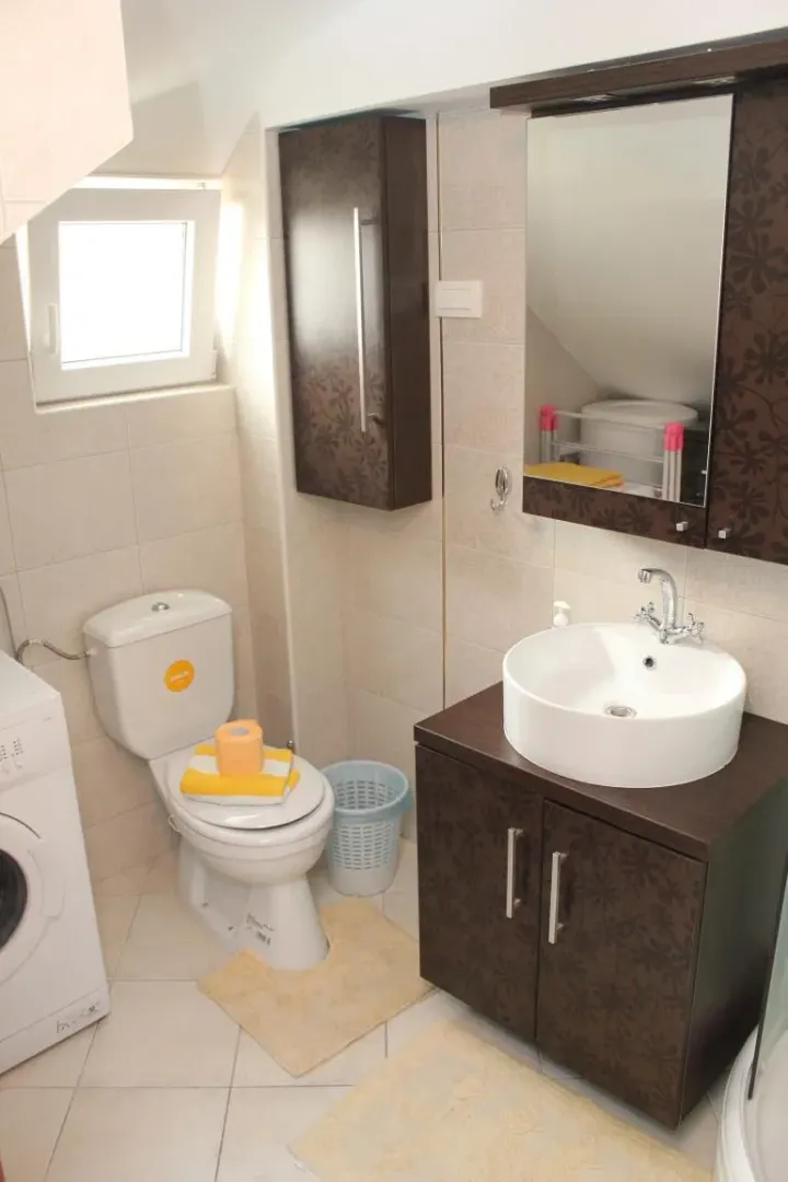 Small bathroom with a sink, toilet, cabinet, and washing machine.