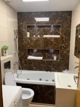 Modernly equipped bathroom with a bathtub and built-in wall niches. - image 6