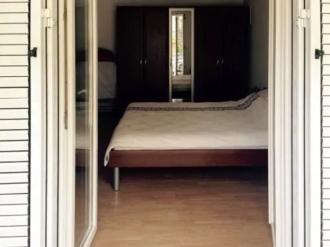 Pogled izvana kroz otvorena balkonska vrata na namještenu spavaću sobu sa bračnim krevetom i ormarom. - image 6