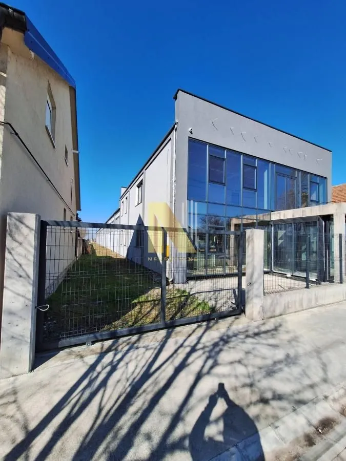 Exterior view of the commercial building with a fence and yard.