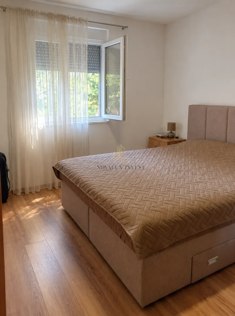 Namještena spavaća soba sa velikim bračnim krevetom i prozorom.