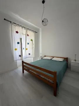 Spavaća soba sa bračnim krevetom, bijelim zidovima i zavjesama sa cvjetnim detaljima. - image 5