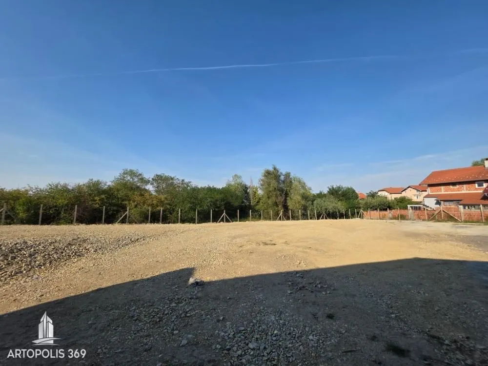 Pogled na ravan plac sa ogradom i rastinjem u pozadini.