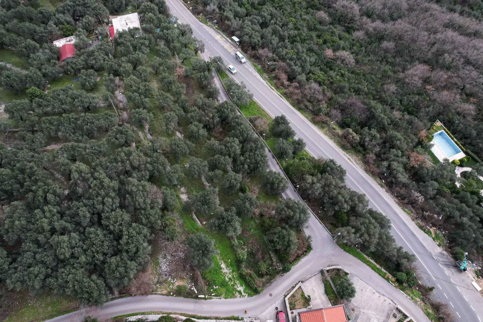 Pogled iz vazduha na zemljište sa putem i zelenilom.