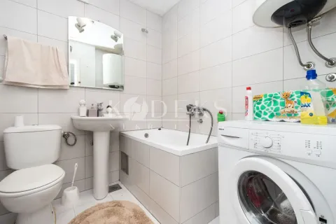 Bathroom equipped with a bathtub, sink, toilet, and washing machine. - image 4