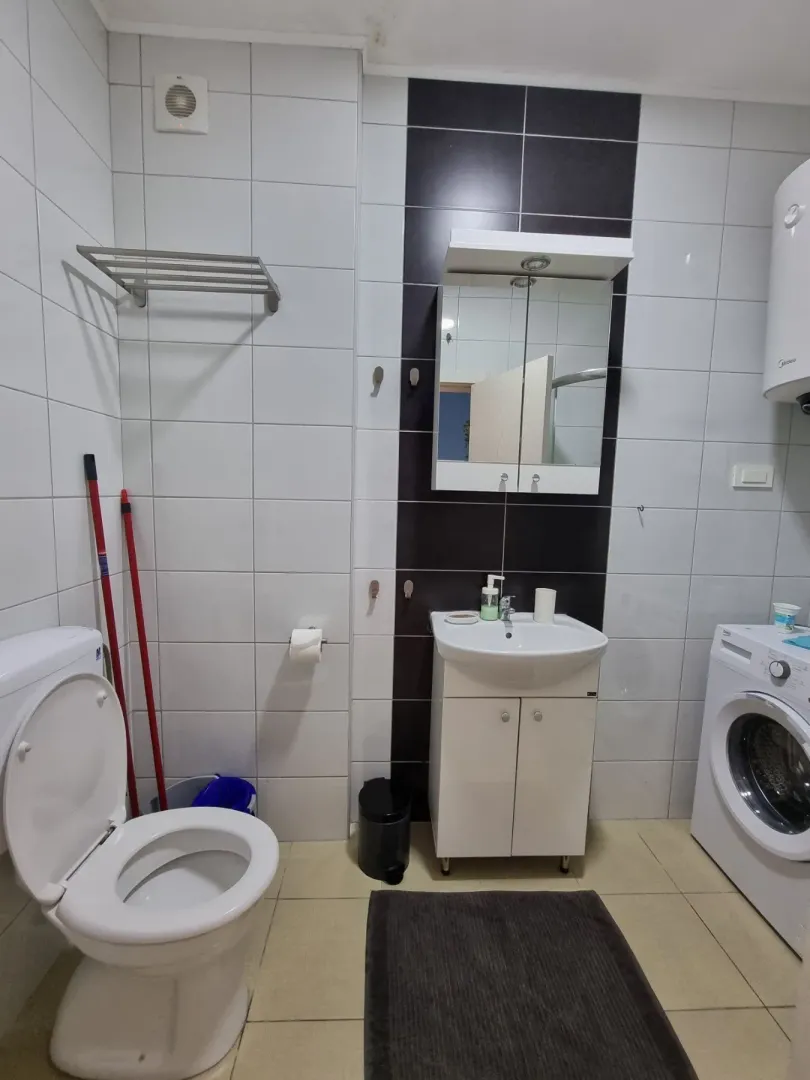 Kupatilo opremljeno sanitarijama, umivaonikom, WC šoljom i veš mašinom.