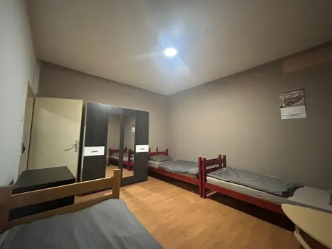 Bedroom with multiple beds and a wardrobe. - image 3